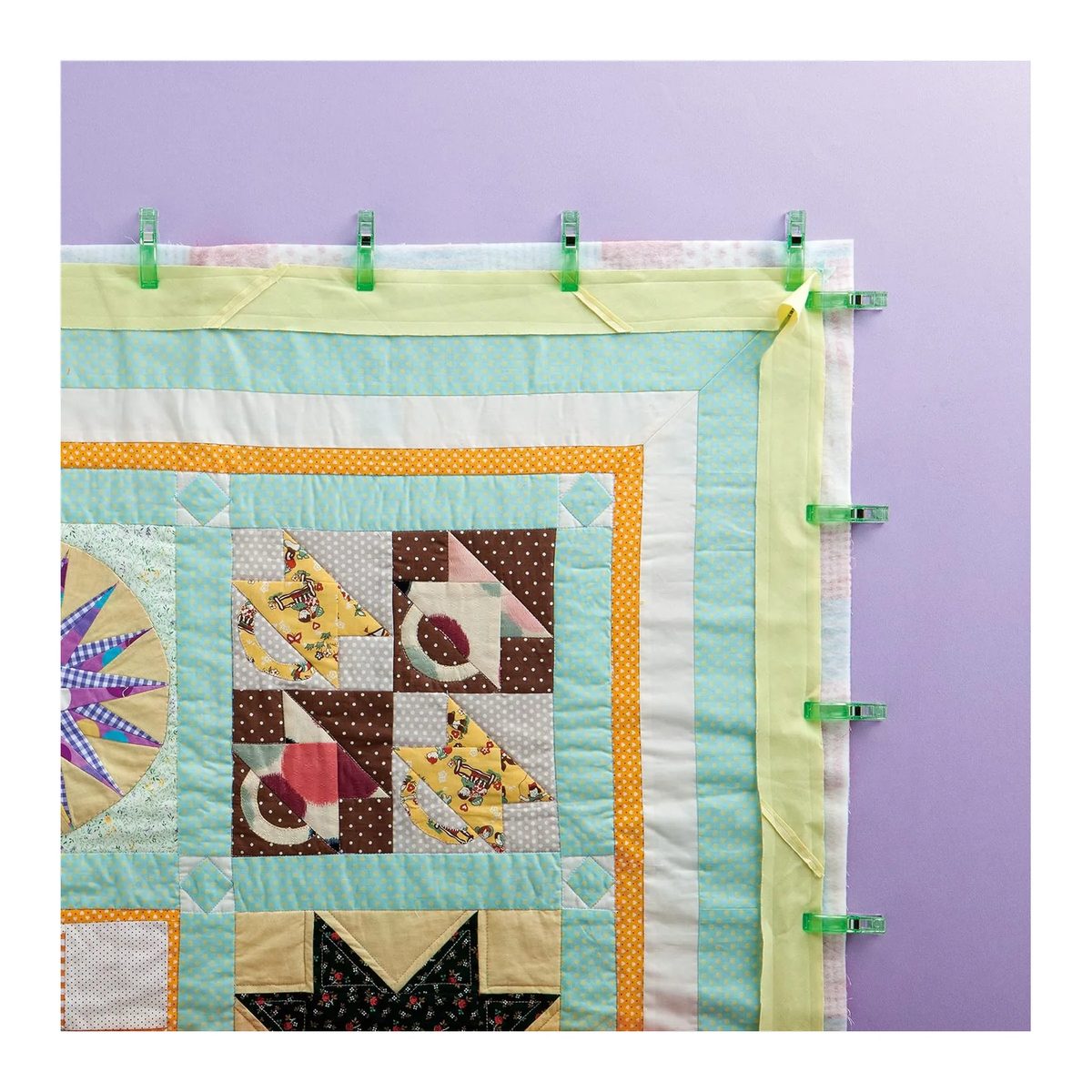 Pinzas Wonder Clips Clover jumbo verdes sujetando el sesgo por el borde de un edredón de patchwork acolchado