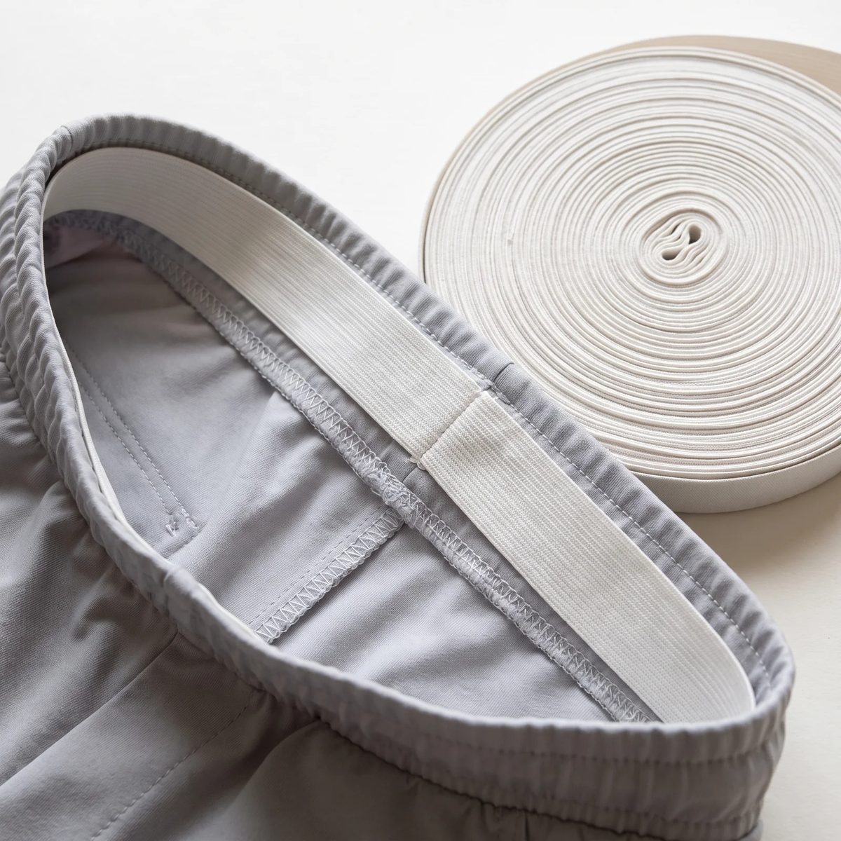 Elástico blanco cosido dentro de la pretina de un pantalón