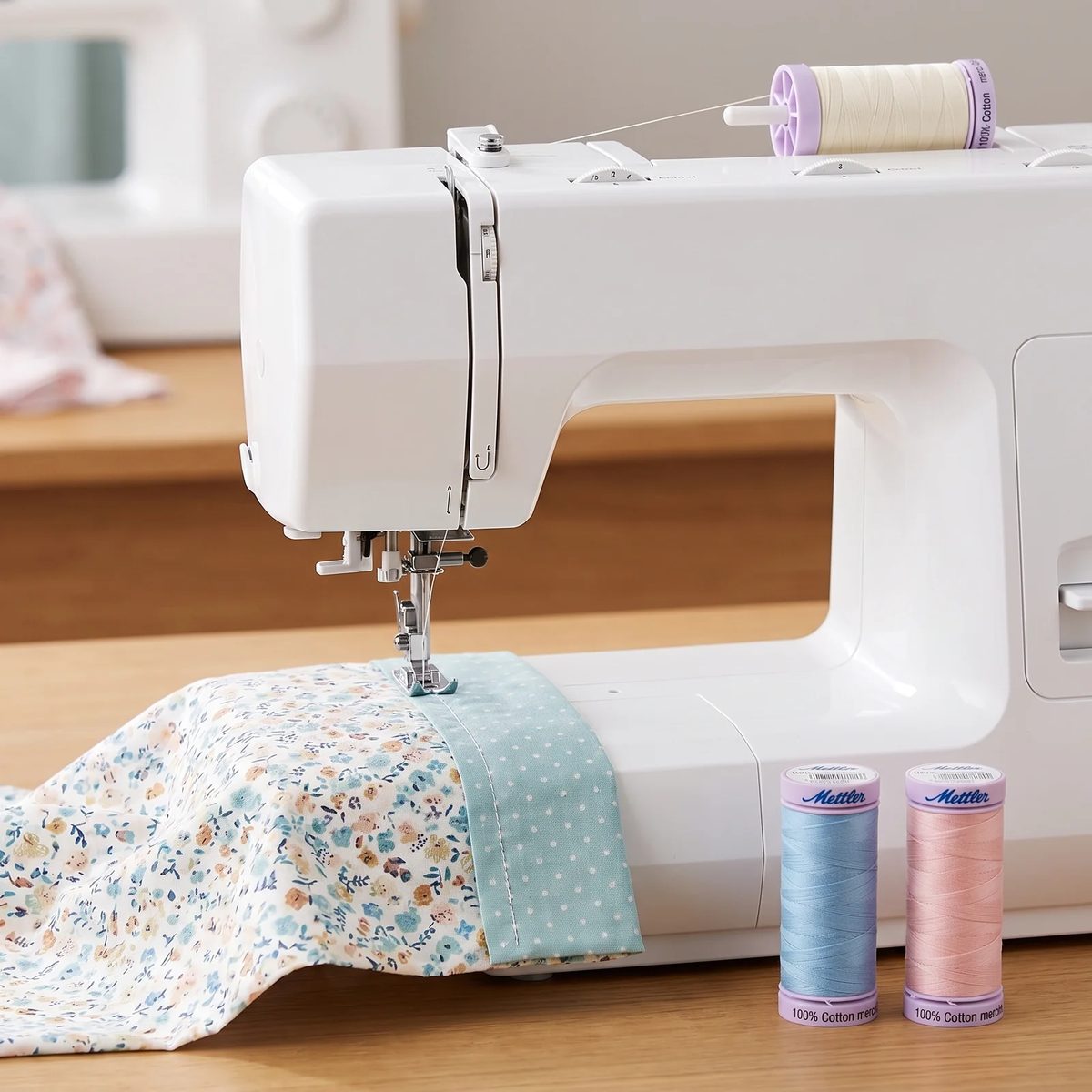 Carrete de hilo Mettler Silk-Finish montado en una máquina de coser casera uniendo dos bloques de patchwork