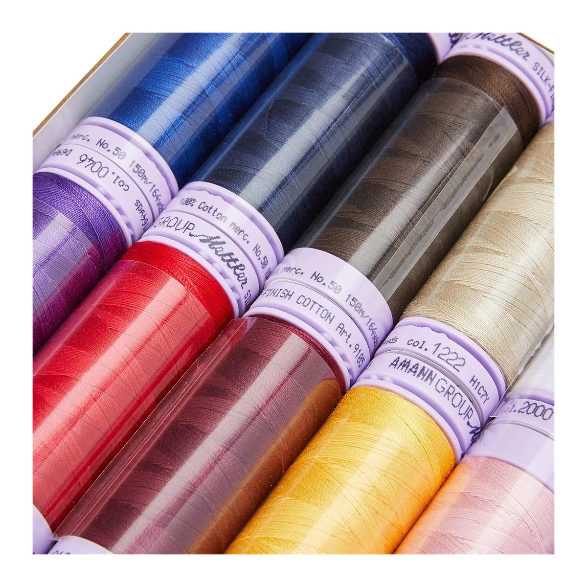 Macro de los carretes Mettler Silk-Finish con la etiqueta lila y el hilo de algodón mercerizado enrollado parejo