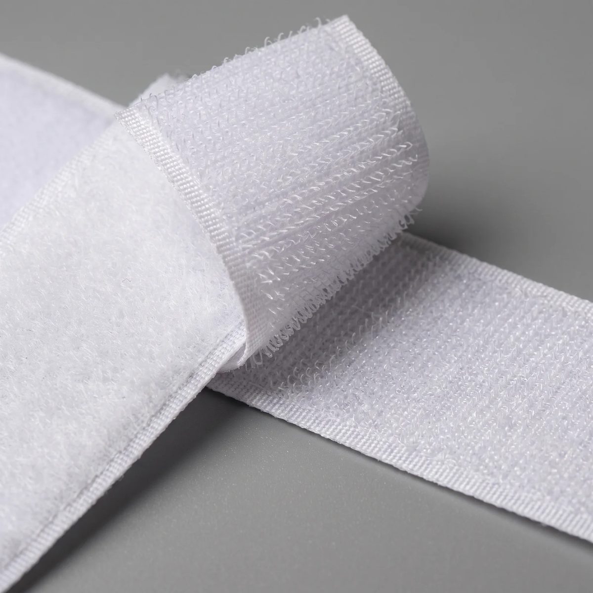Macro del velcro blanco: la cinta de ganchos y la de bucles una junto a otra, enganchadas por un extremo