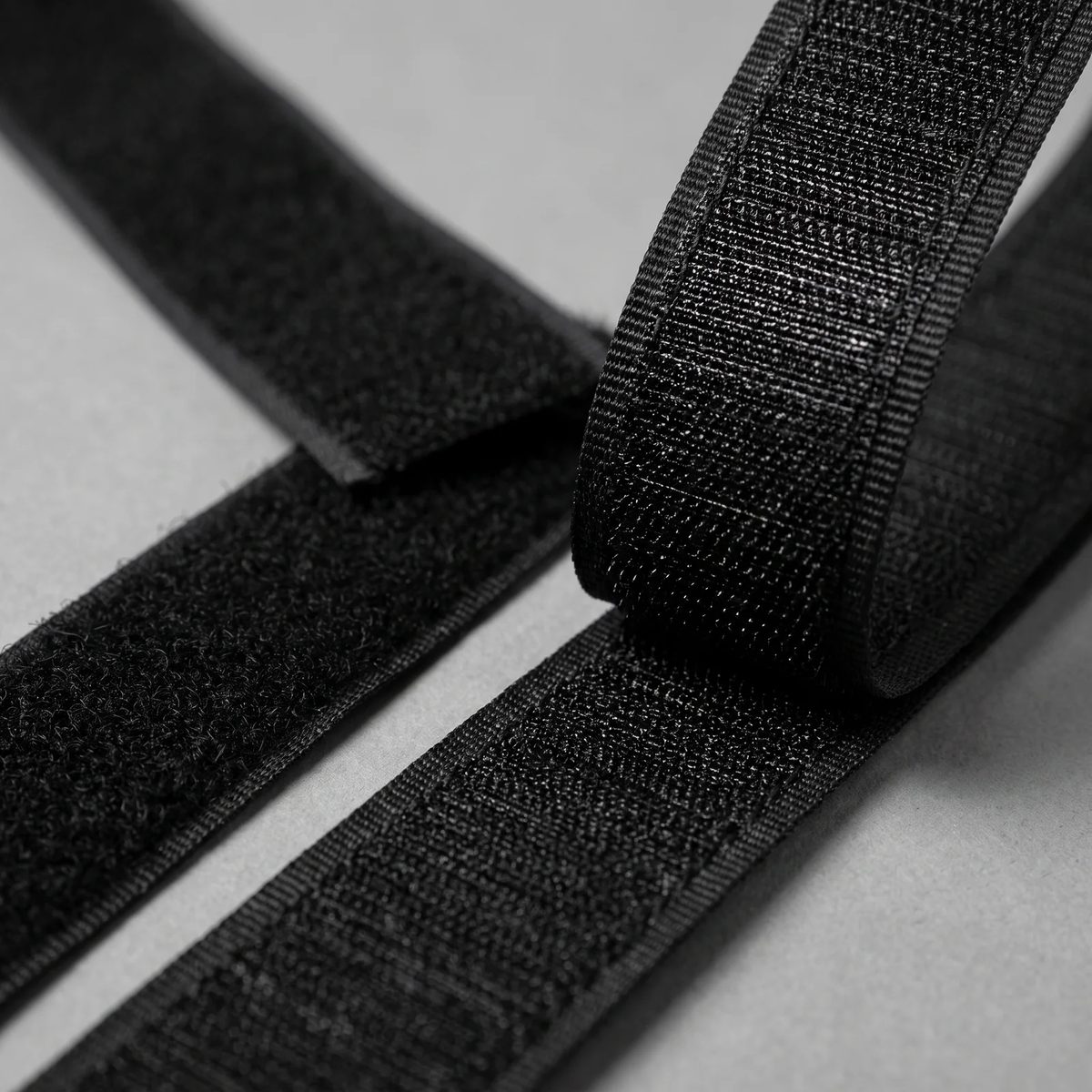 Macro del velcro negro: la cinta de ganchos y la de bucles una junto a otra, enganchadas por un extremo