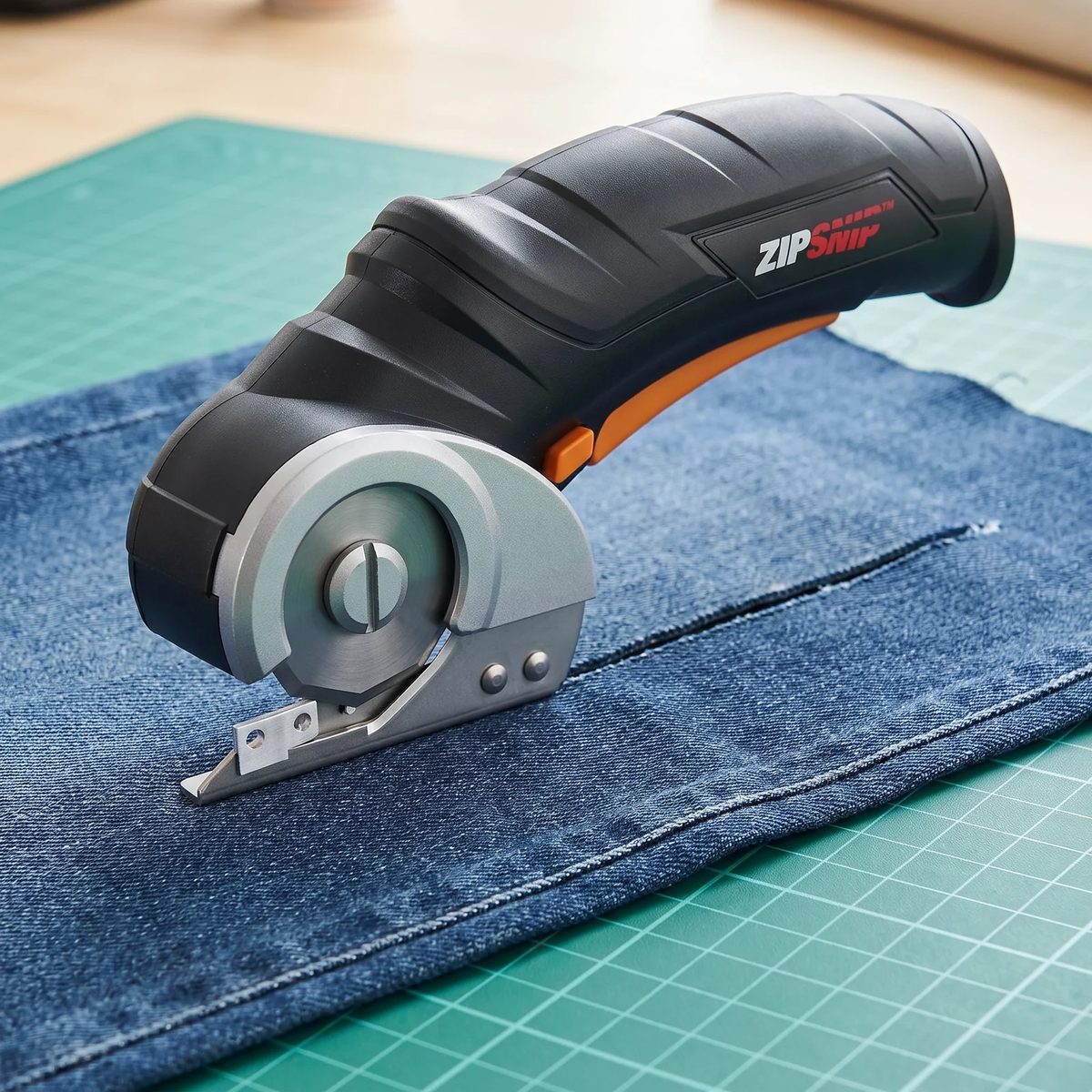 Tijeras eléctricas WORX ZipSnip al final de un corte recto en una tela de jean sobre tapete de corte