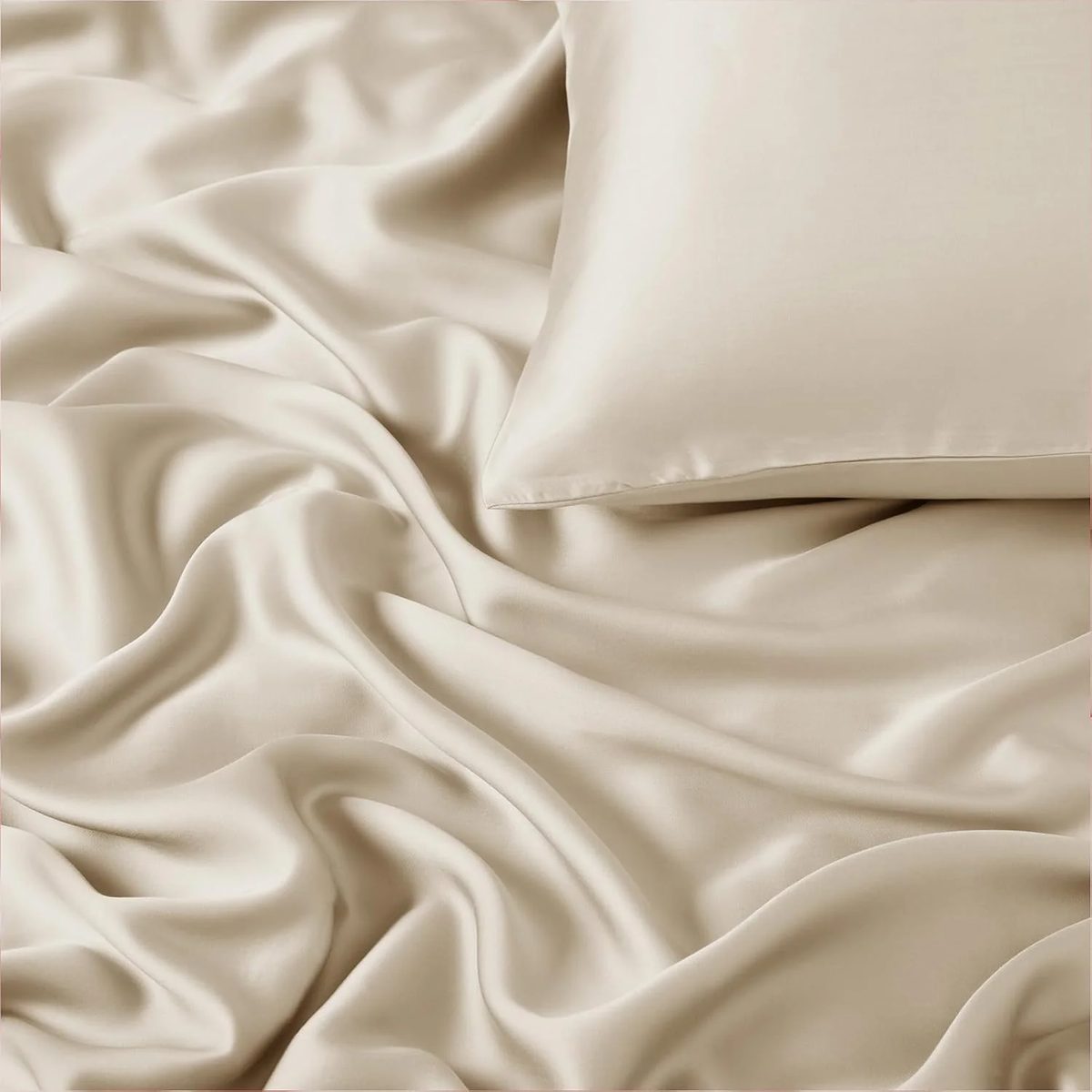 Tencel de Algodón color beige, extendida sobre una cama junto a una almohada